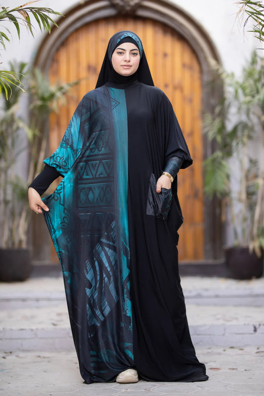 Woman wearing a black abaya with a blue patterned cover-up in an outdoor setting.