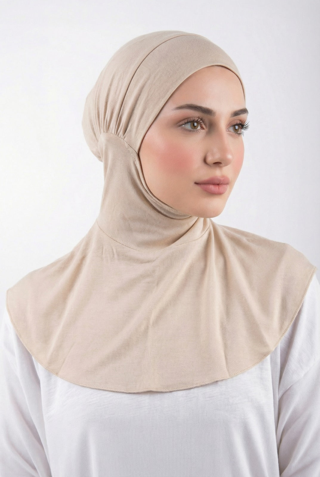 Woman wearing a beige hijab against a white background