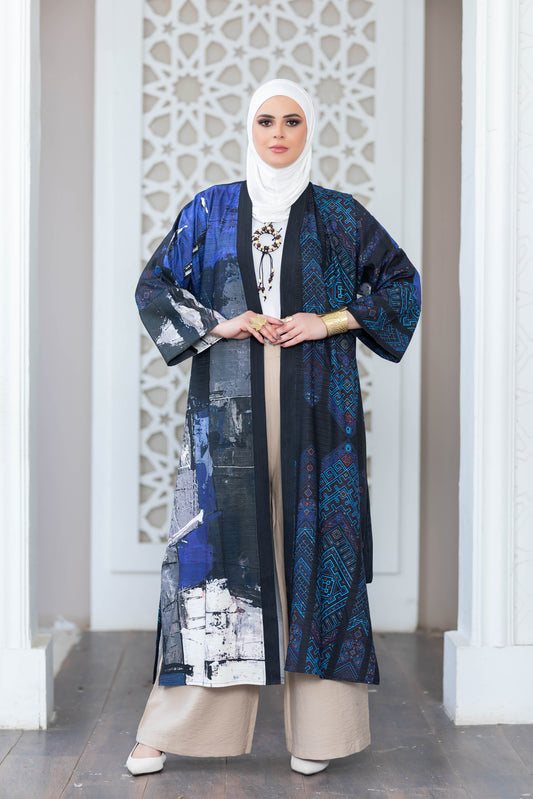 Elegant patterned kimono with vibrant blue and black tones, worn over a simple white outfit, against a backdrop of an intricate white architectural design.