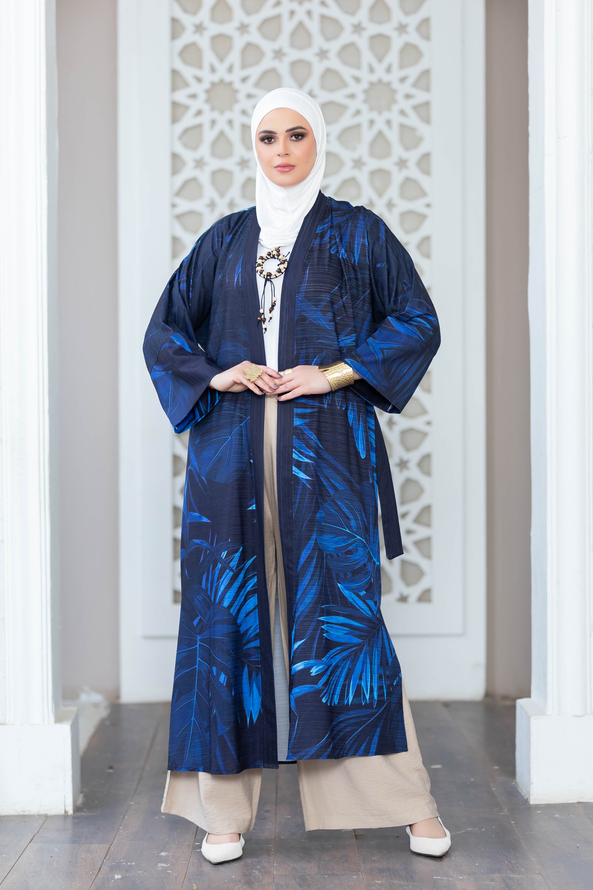 Elegant blue kimono with floral print, worn by a woman in traditional Islamic dress, posing in front of ornate white architecture.