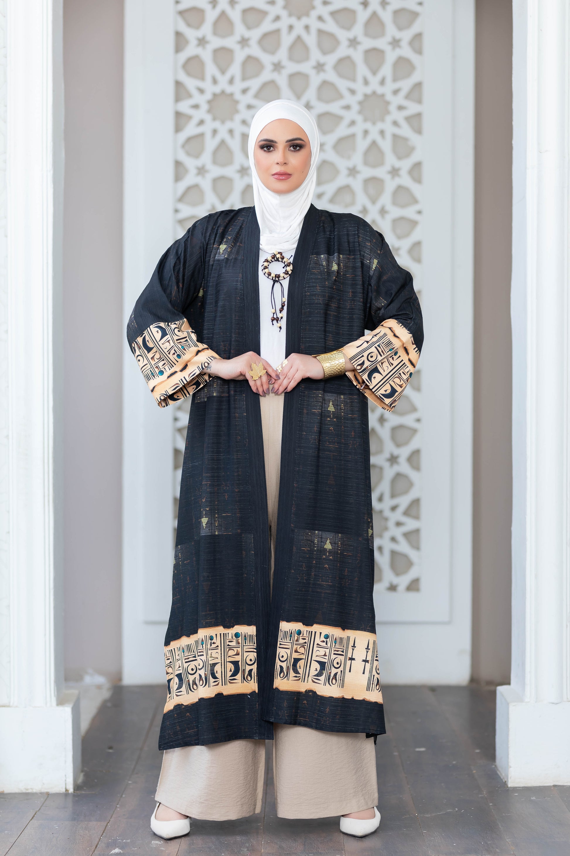 Elegant printed black kimono with decorative embroidered cuffs, displayed against a white geometric pattern backdrop.