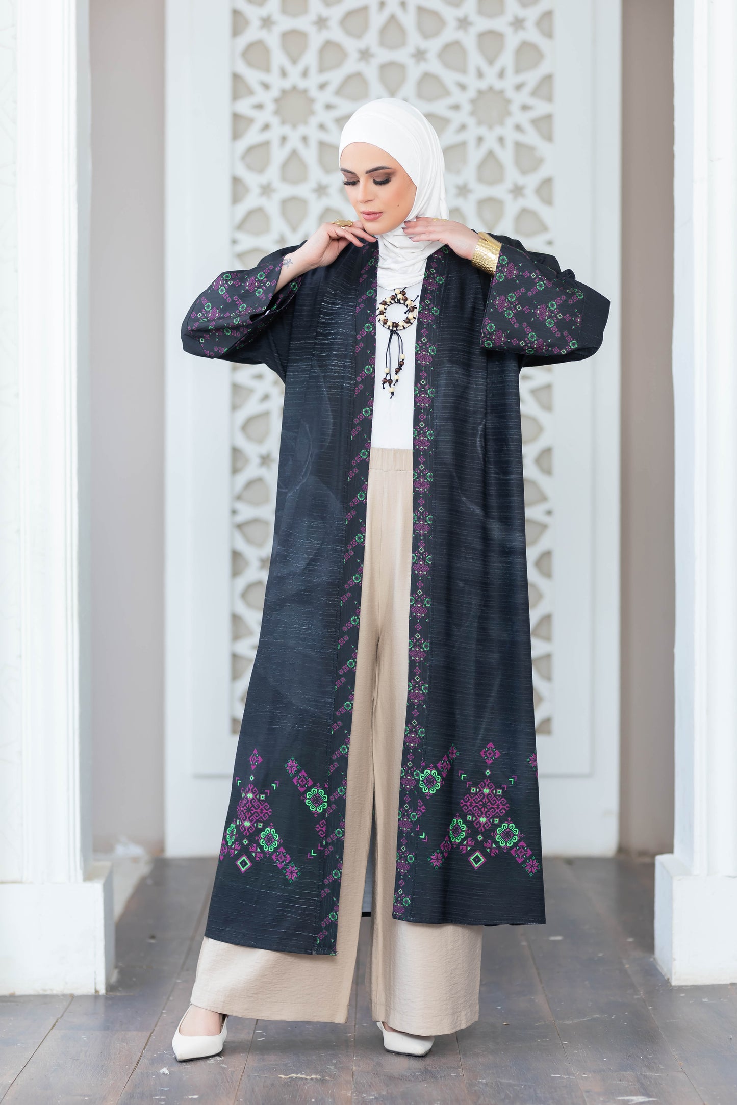 Elegant floral kimono with long sleeves, worn by a woman in traditional Islamic clothing against a decorative white wall.