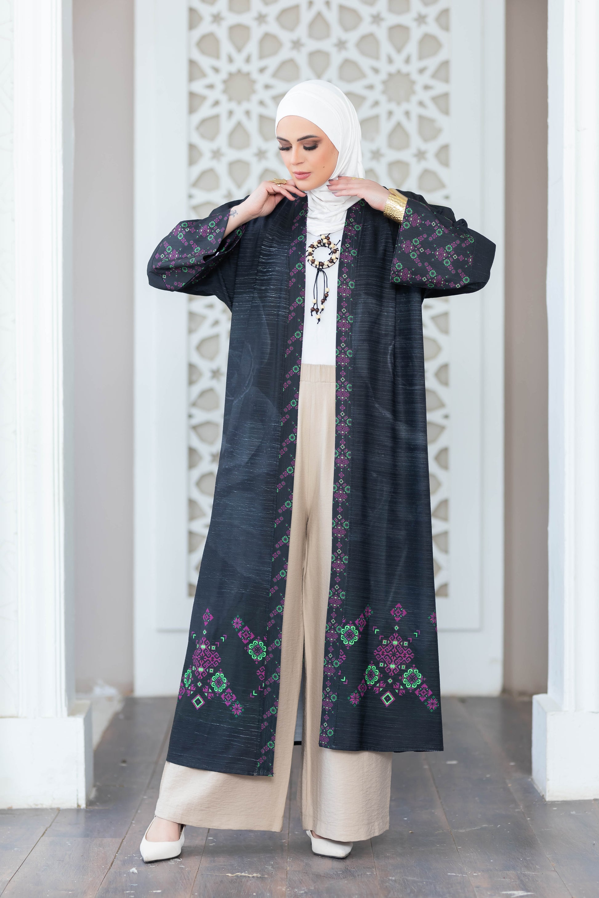 Elegant floral kimono with long sleeves, worn by a woman in traditional Islamic clothing against a decorative white wall.