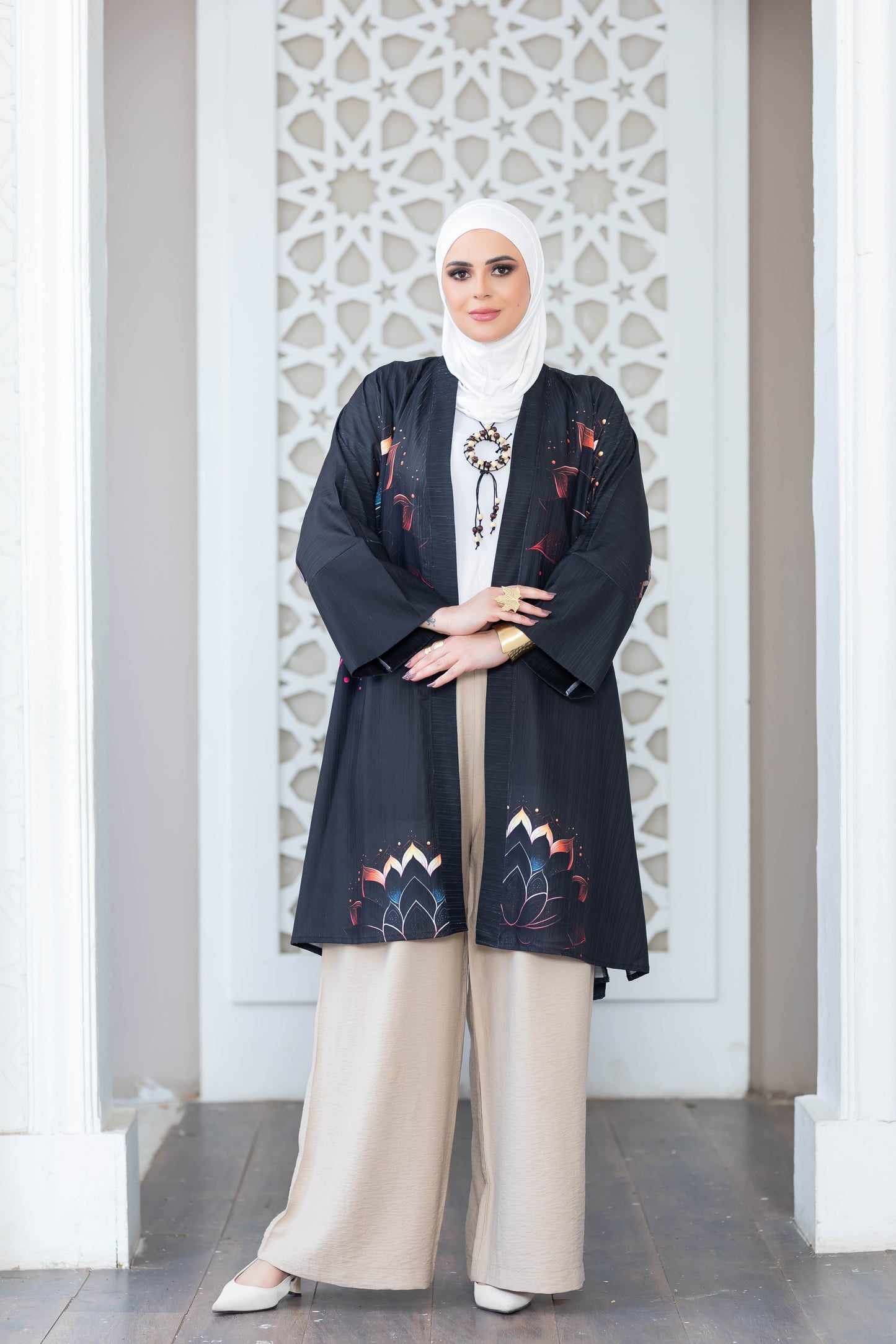 Stylish patterned kimono in monochrome colors, worn by a woman with hijab in front of an ornate white architectural backdrop.