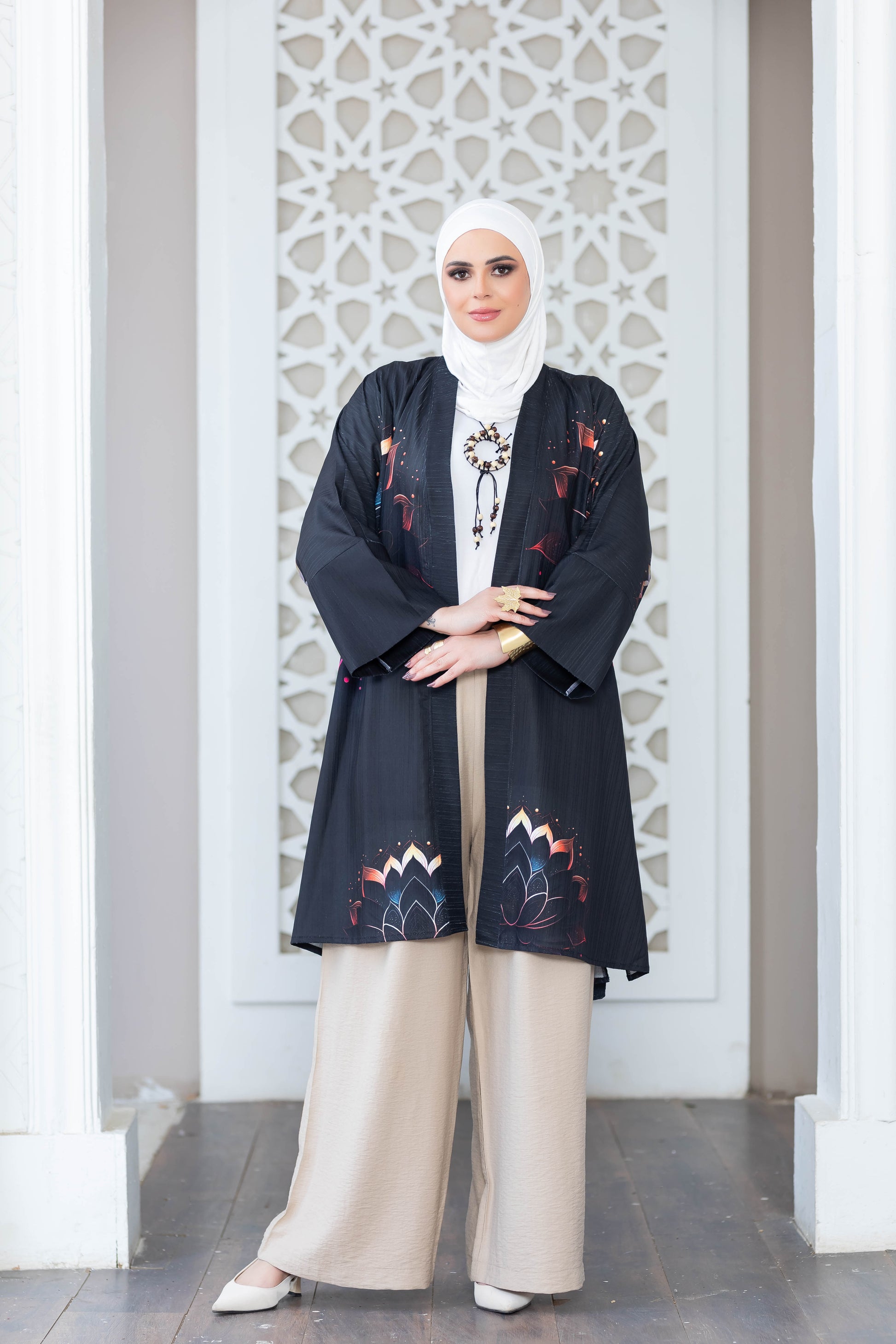 Stylish patterned kimono in monochrome colors, worn by a woman with hijab in front of an ornate white architectural backdrop.