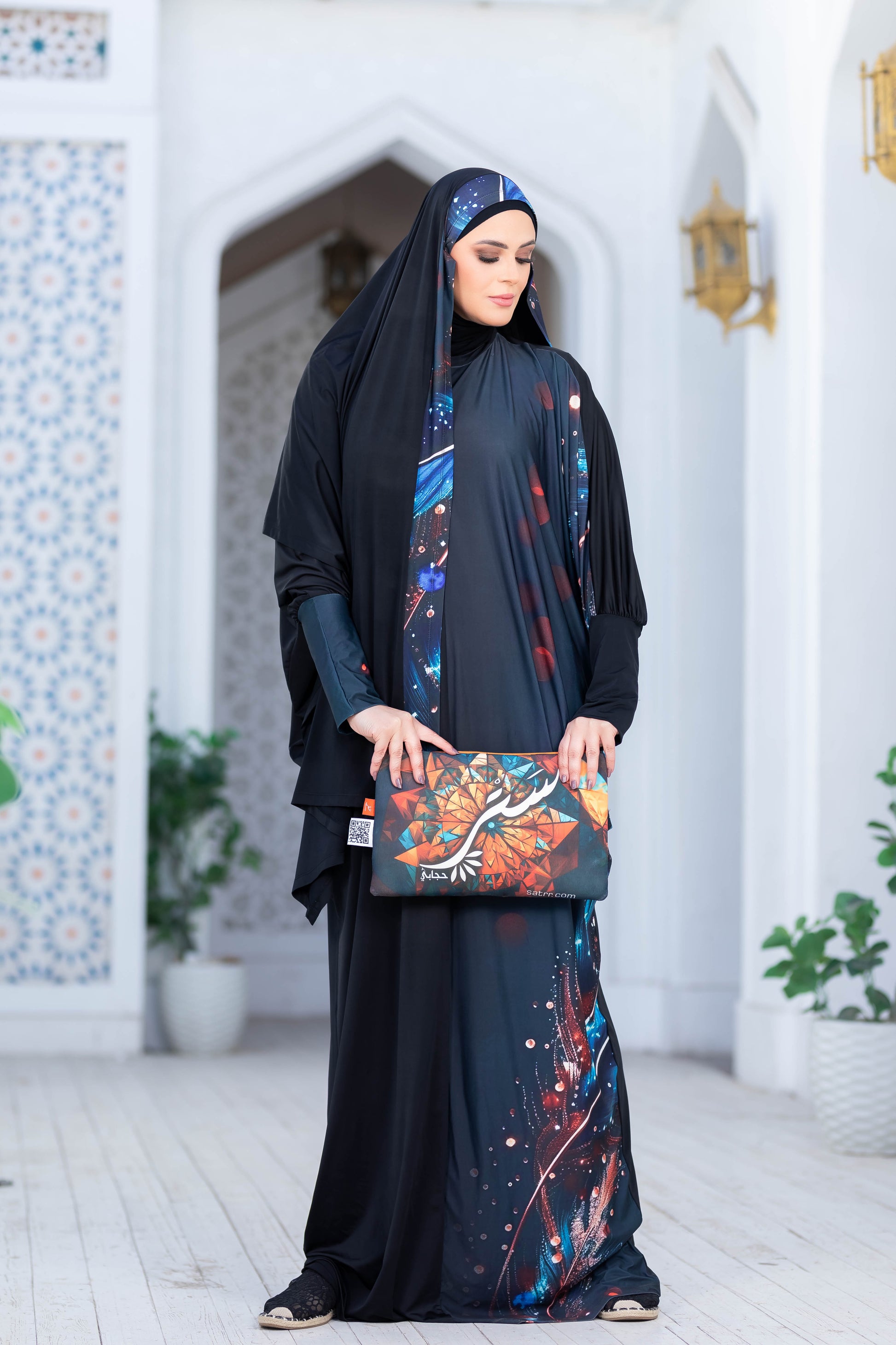 Modest Isdal 777175: Traditional Muslim woman in elegant black abaya with floral patterns, standing in front of an ornate doorway.