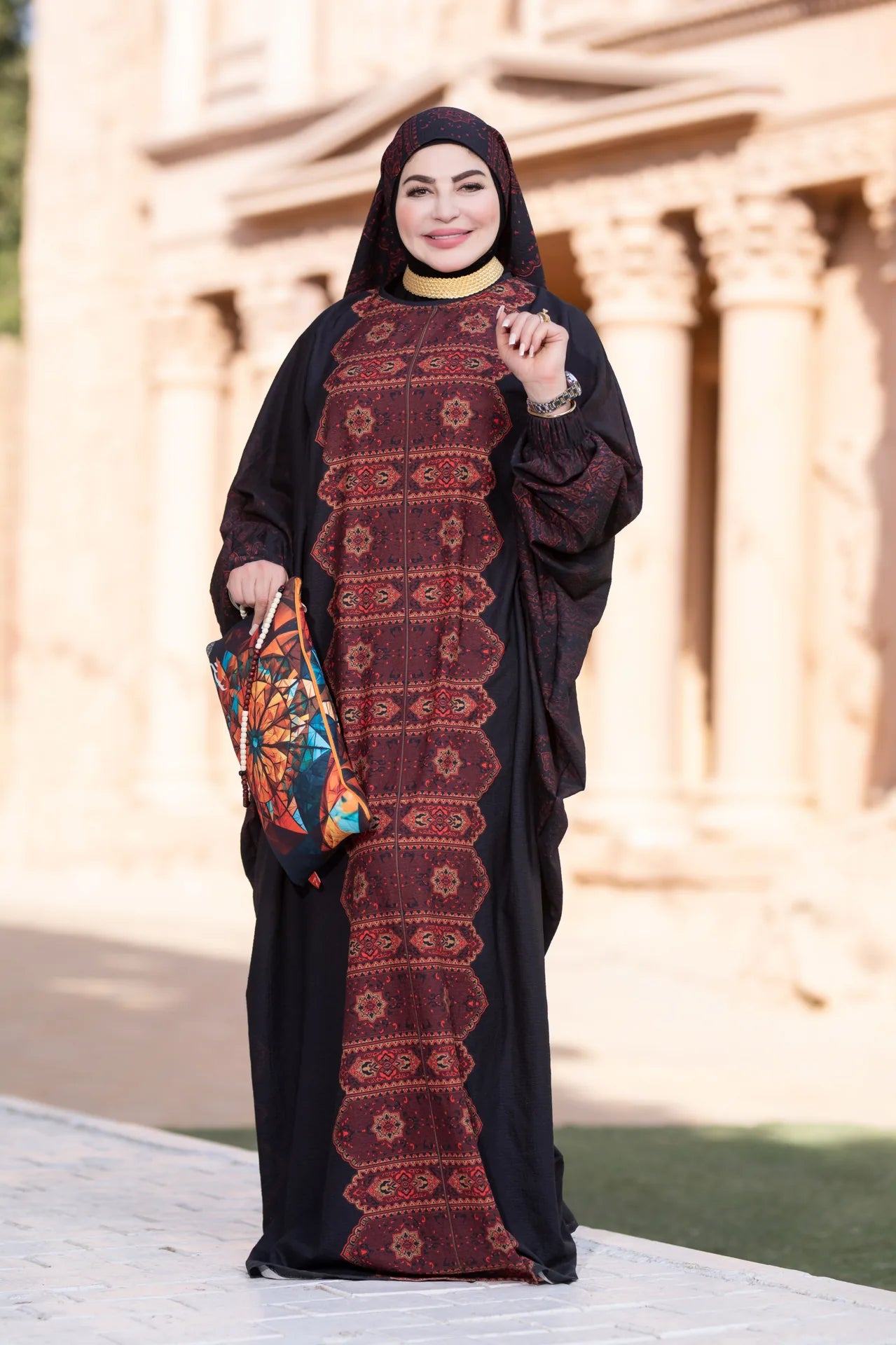 Woman in a black and red patterned dress standing in front of a classical building.