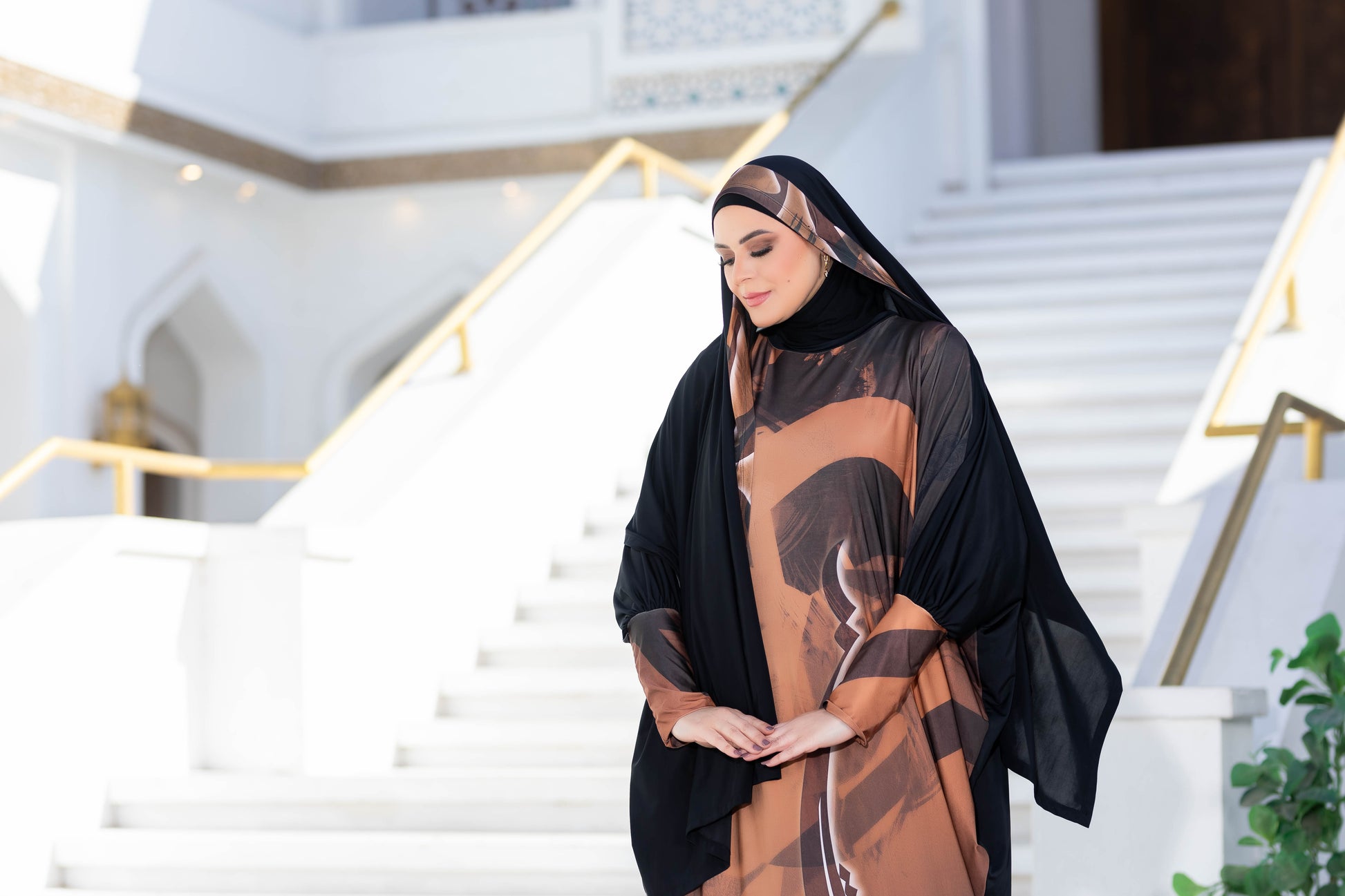 Modest women's abaya with a modern color-block design, worn by a woman walking down steps.