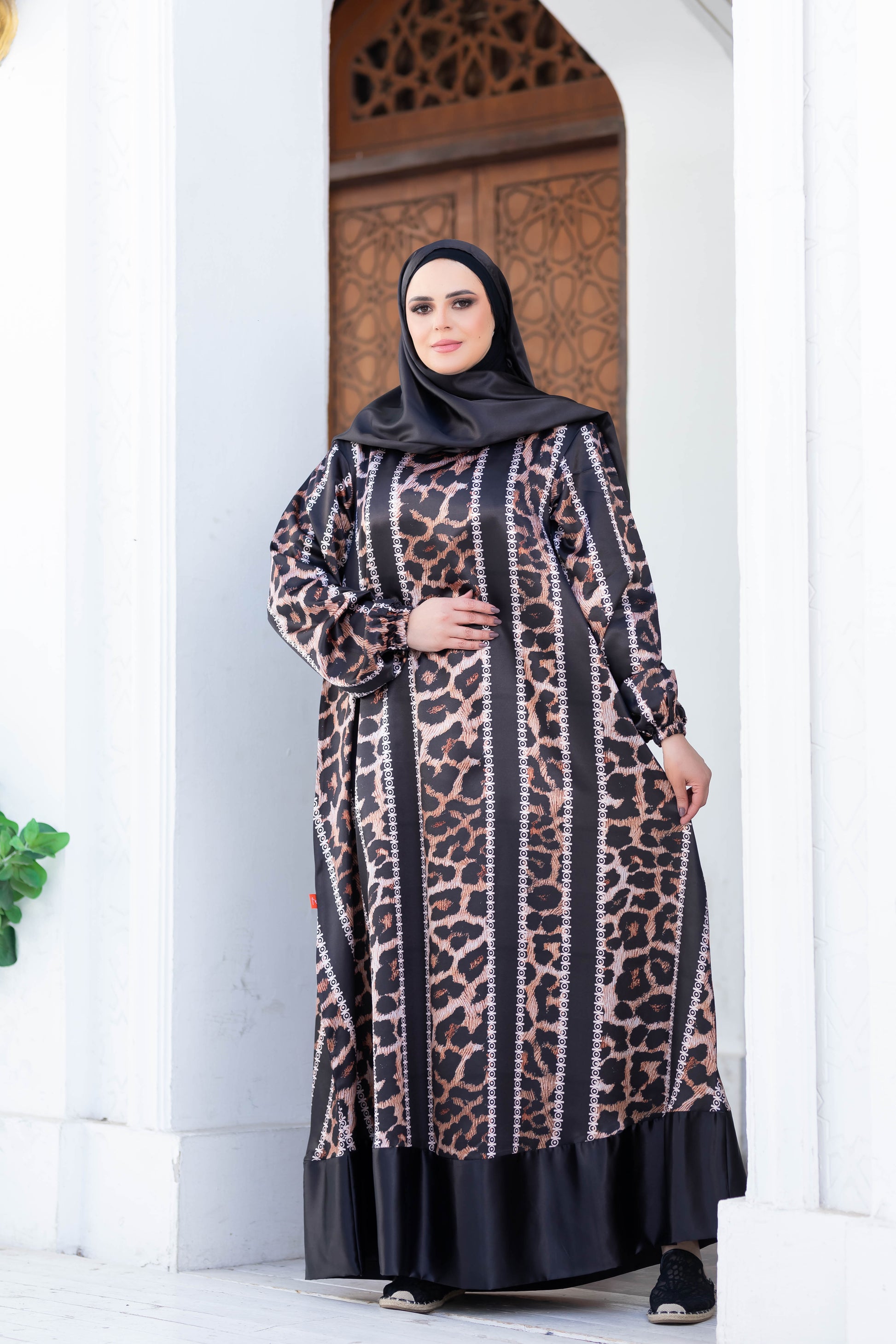 Elegant modest dress featuring an ornate leopard print pattern and long sleeves, worn in a scenic outdoor setting.