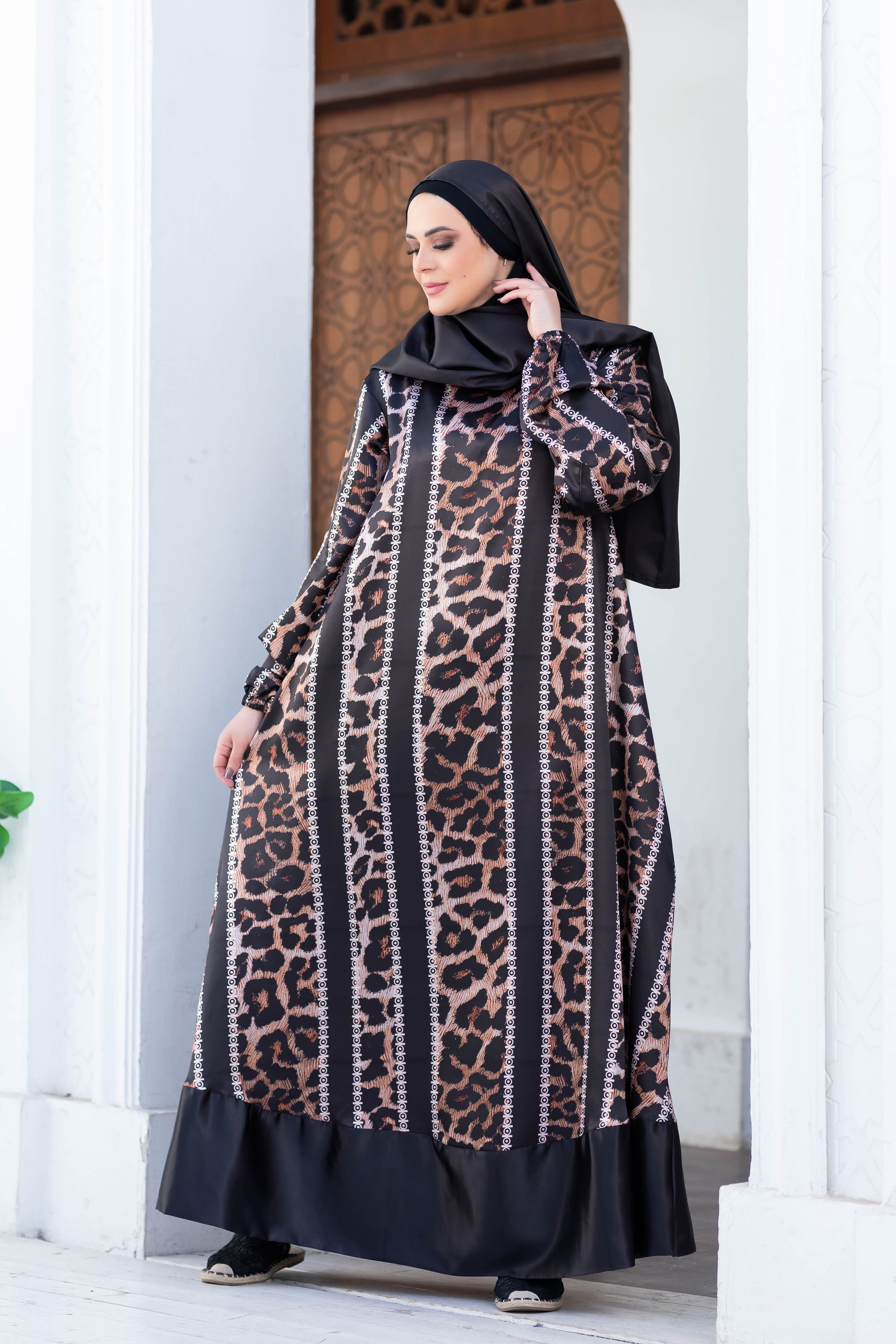 Modest dress 777188 featuring a leopard print pattern with contrasting black details, styled with a long flowing silhouette and hijab.