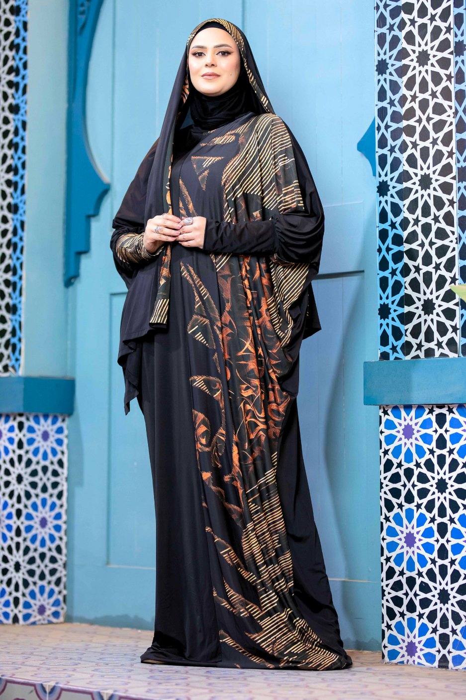 Stylish Islamic dress featuring intricate patterns and bold colors, modestly showcasing the subject's graceful posture against a vibrant, ornate backdrop.