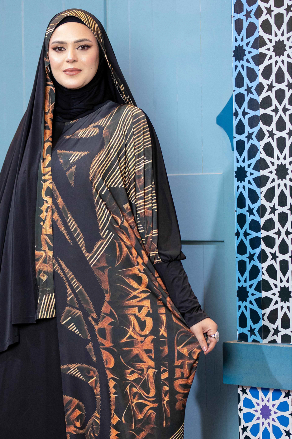 Stylish Islamic fashion apparel showcasing an ornate printed dress and hijab against a vibrant, patterned background.