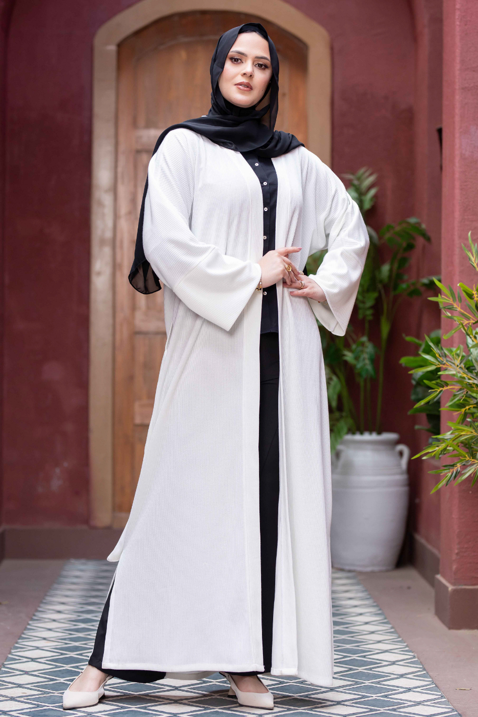 Long white kimono with wide sleeves and black accents worn by a woman in front of a wooden arch