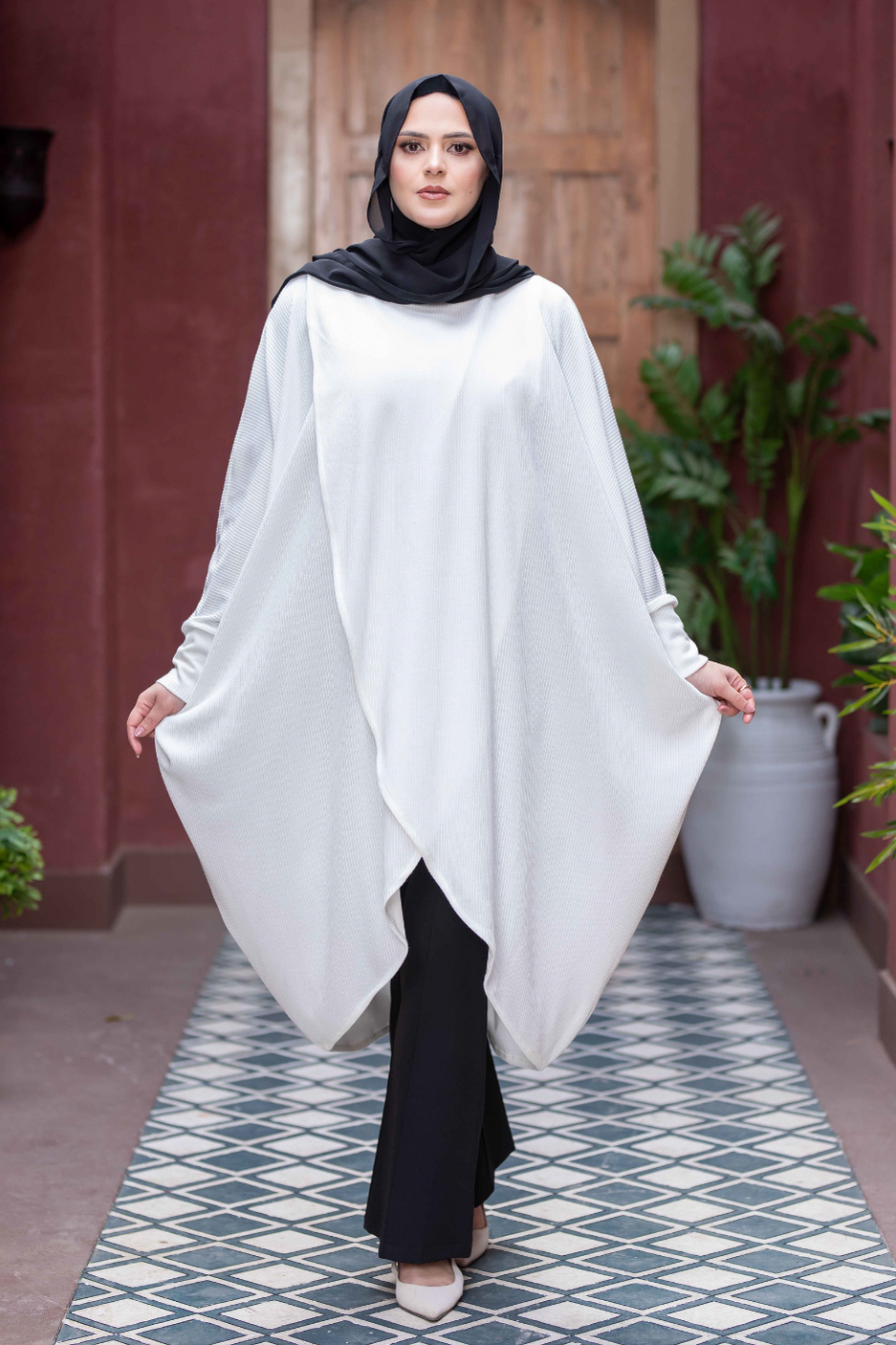 Elegant Kimono Cardigan: Stylish white robe with flowing sleeves, worn by a woman in a hijab against a rustic backdrop.