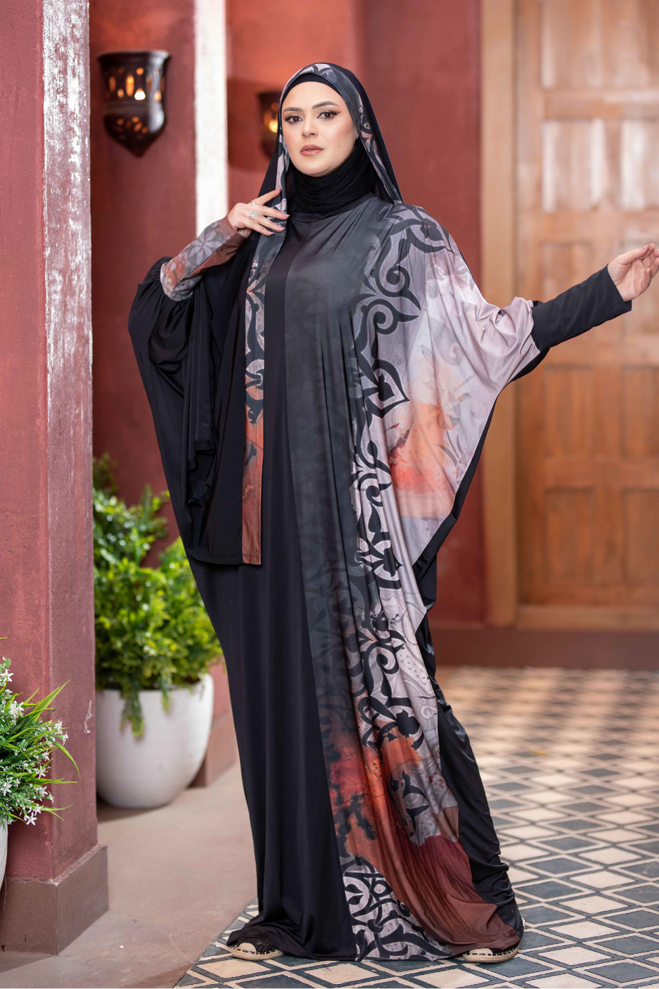 Elegant Islamic headdress: Detailed gray and black printed Hijab with tasseled shawl over modern modest dress, standing in traditional architectural setting.