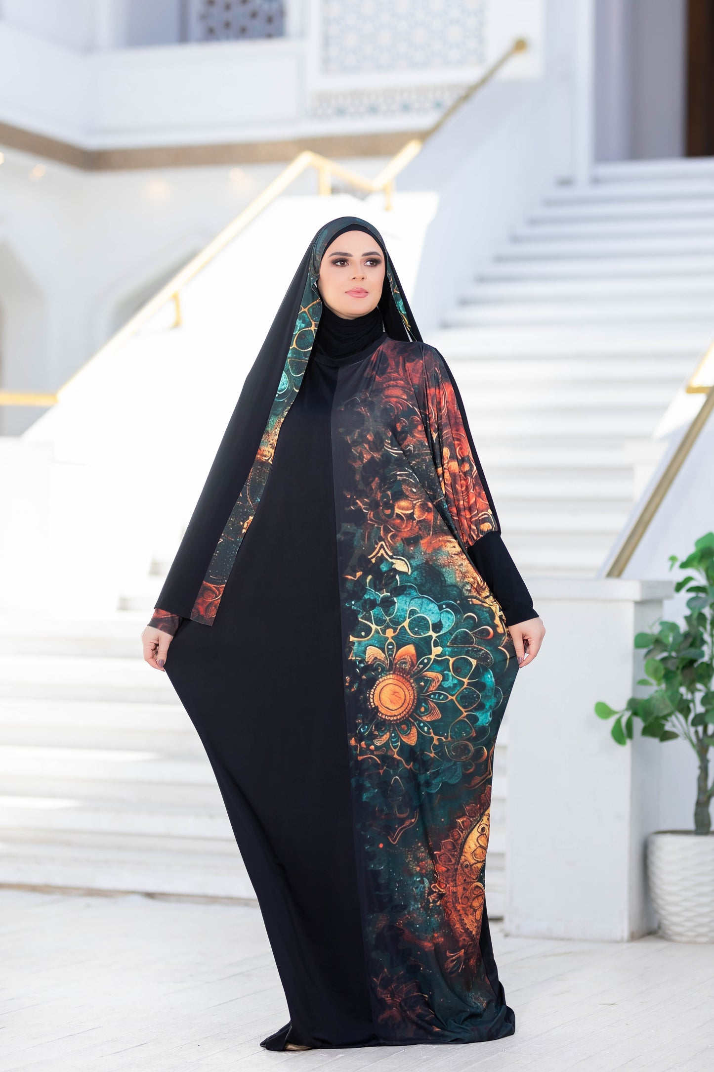 Modest floral abaya with vibrant, multicolored floral pattern against a black background, worn by a woman standing on stone steps.