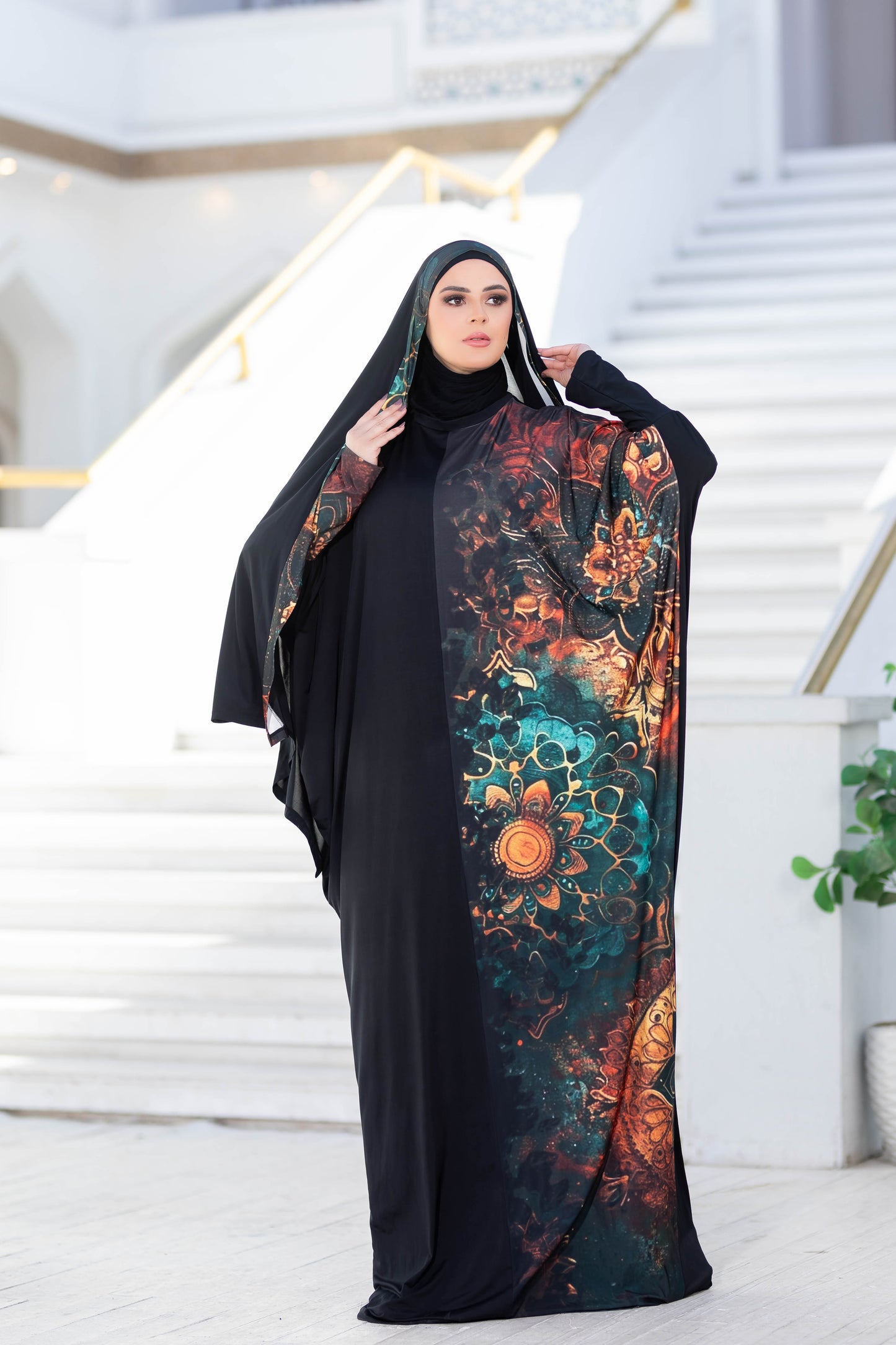 Modest floral patterned robe and black abaya worn by a woman on steps