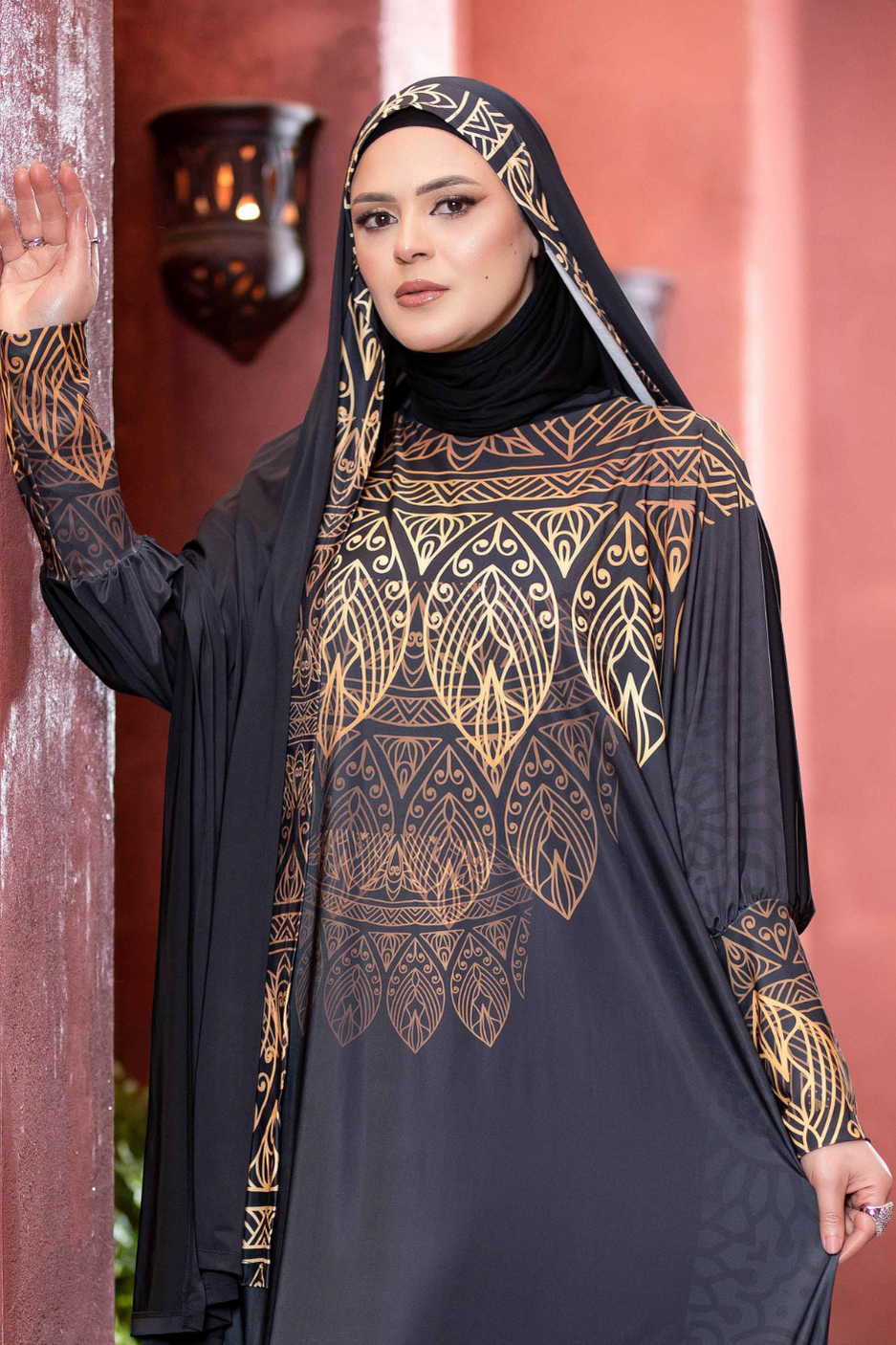 Elegant black and gold printed Islamic dress with headpiece, showcasing traditional Arabian fashion.