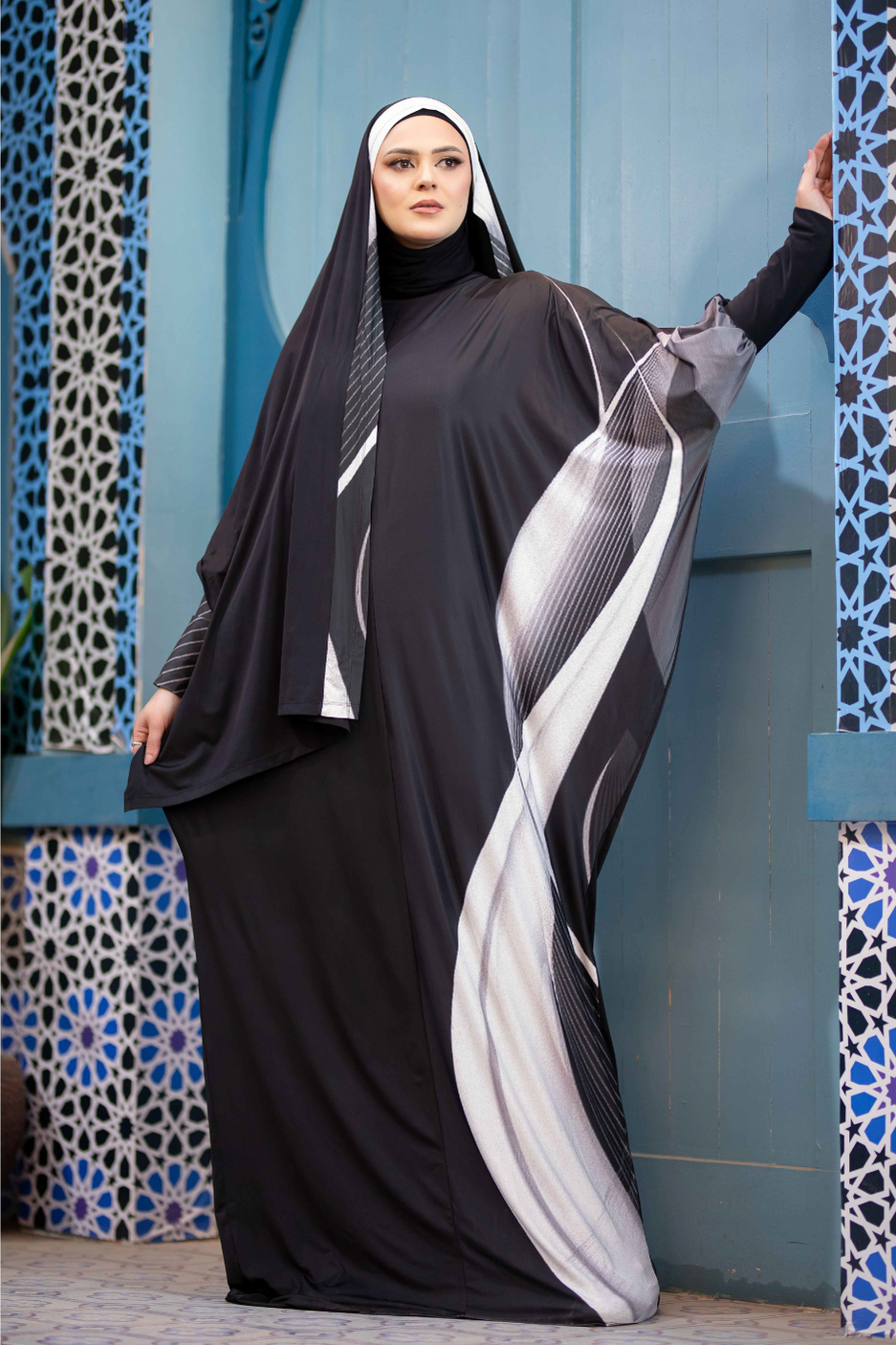 Satr Hejab 777173 - Elegant modest dress with flowing abaya in contrasting colors, worn by a woman in traditional Islamic attire against a patterned wall.