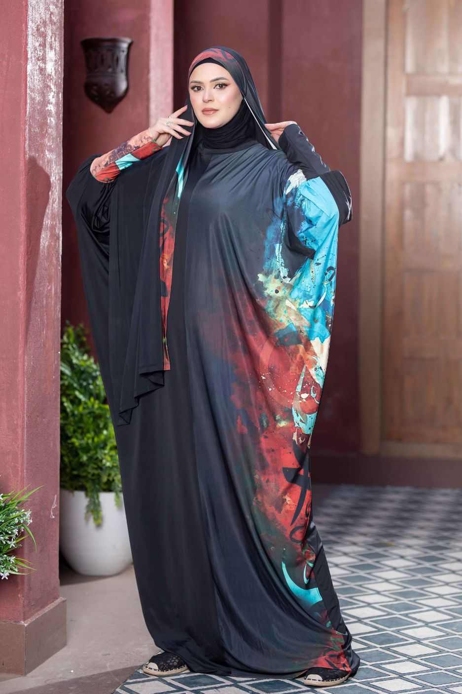 Elegant Islamic attire on display in Satr store. Flowing black hijab accentuated by vibrant floral patterns, highlighting modest fashion trends.