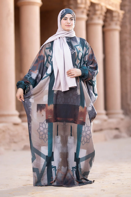 Woman in a patterned dress and hijab standing in front of classical architecture.